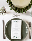 Platzkarte auf dem Tisch über dem Teller liegend. Teil der Tischdekoration Hochzeit neben Blumen, Tischnummern und Kerzen.