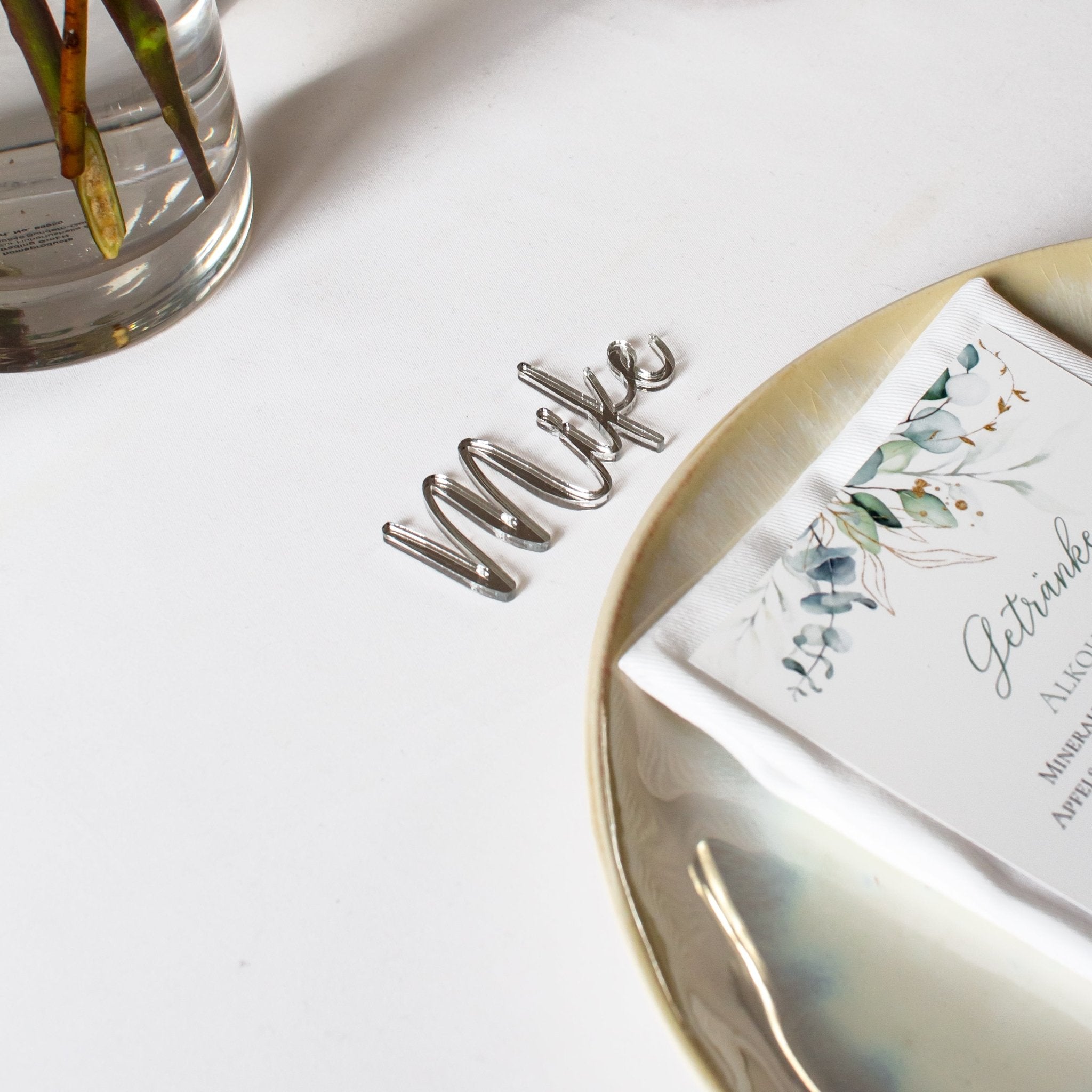 Tischkärtchen Silber personalisiert mit dem Namen liegend über dem Teller als Dekoration auf dem Tisch der Hochzeitsfeier.